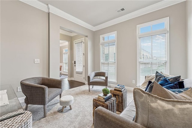 living area featuring ornamental molding, visible vents, baseboards, and wood finished floors