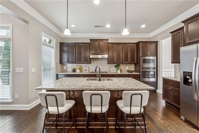 kitchen with visible vents, appliances with stainless steel finishes, a sink, dark brown cabinets, and backsplash