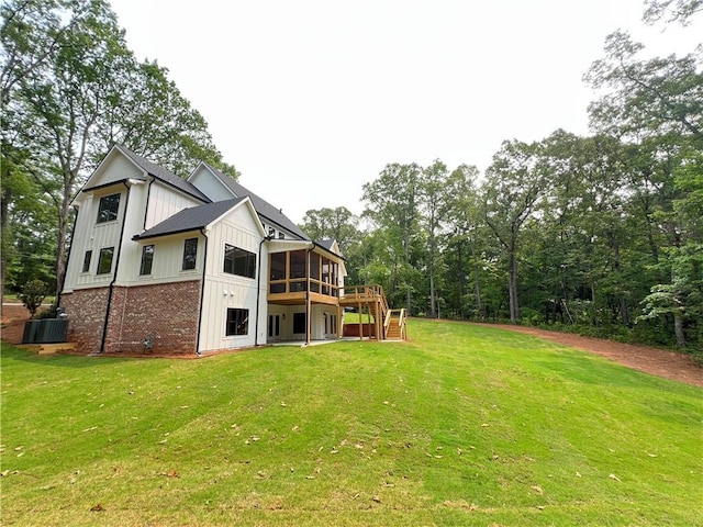 356 Henry Scott Rd, Ball Ground, GA 30107 - rear view of house with central air condition unit, a sunroom, board and batten siding, a wooden deck, and a lawn