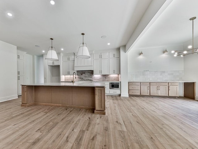 356 Henry Scott Rd, Ball Ground, GA 30107 - kitchen with backsplash, light wood-style flooring, light countertops, white cabinets, and a large island with sink