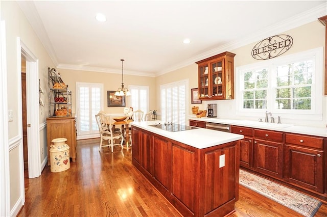 kitchen featuring dark wood-type flooring, sink, crown molding, decorative light fixtures, and a kitchen island