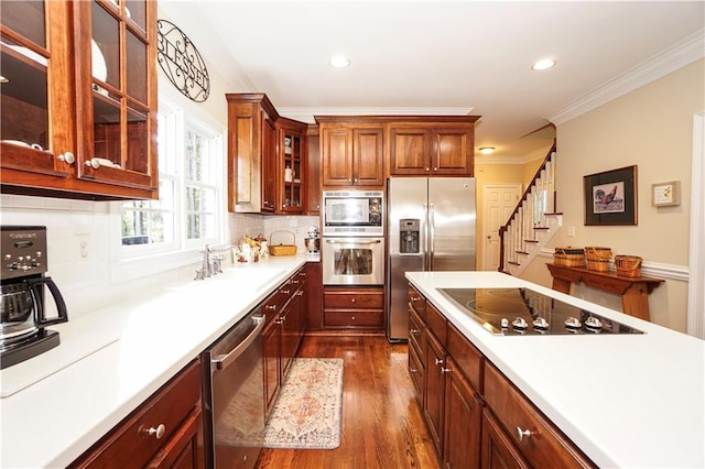 kitchen featuring sink, dark hardwood / wood-style flooring, backsplash, appliances with stainless steel finishes, and ornamental molding