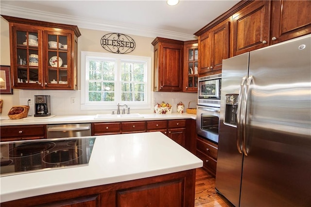 kitchen featuring sink, stainless steel appliances, tasteful backsplash, ornamental molding, and hardwood / wood-style flooring