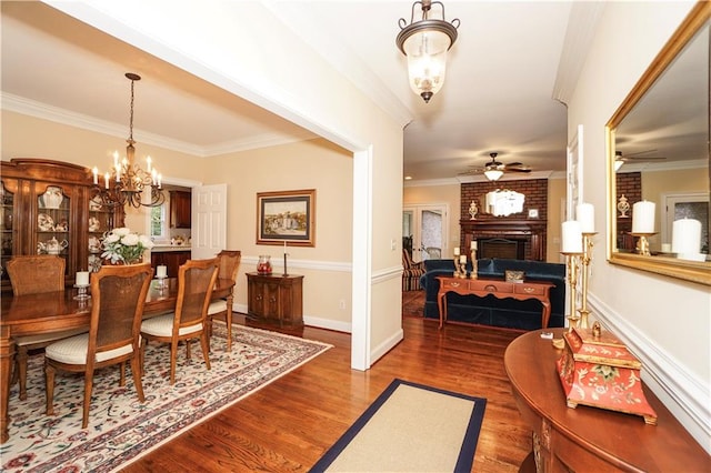 dining area featuring hardwood / wood-style floors, ceiling fan with notable chandelier, crown molding, and a fireplace