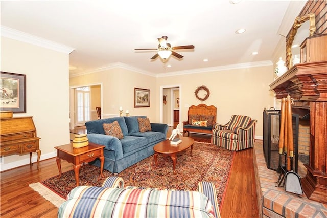 living room with crown molding, a fireplace, ceiling fan, and hardwood / wood-style flooring