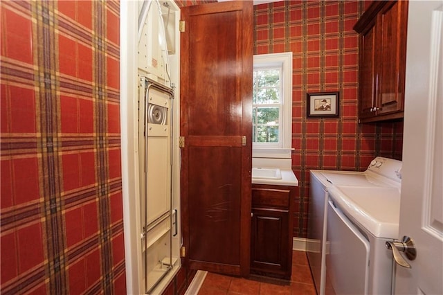 clothes washing area featuring tile patterned floors, washer and dryer, and cabinets