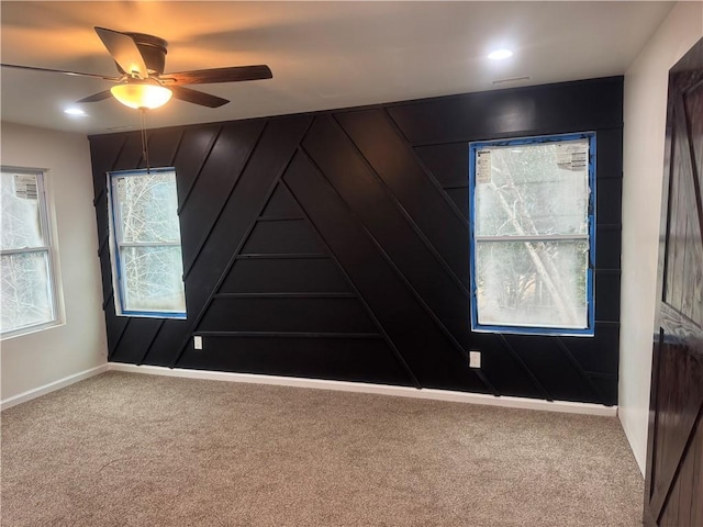 carpeted empty room featuring ceiling fan and baseboards