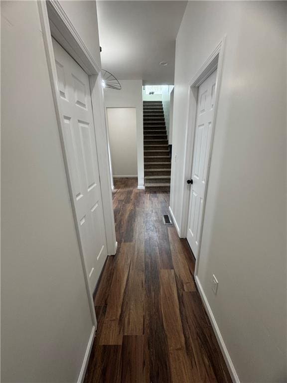 hallway with baseboards, visible vents, stairway, and dark wood-style flooring