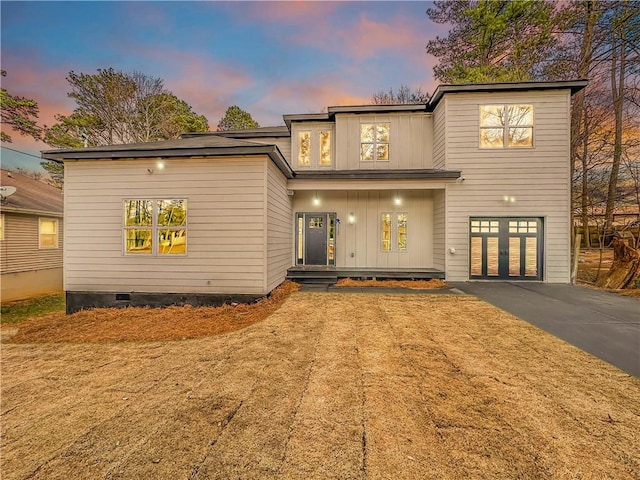 view of front facade with driveway, crawl space, an attached garage, covered porch, and board and batten siding