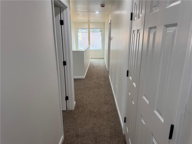 hallway with dark colored carpet and baseboards