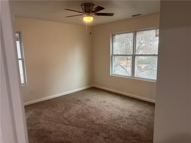 spare room featuring carpet flooring, ceiling fan, visible vents, and baseboards