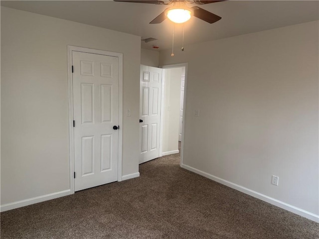 spare room with visible vents, dark colored carpet, a ceiling fan, and baseboards