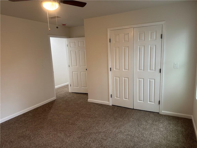 unfurnished bedroom with a closet, dark carpet, visible vents, and baseboards