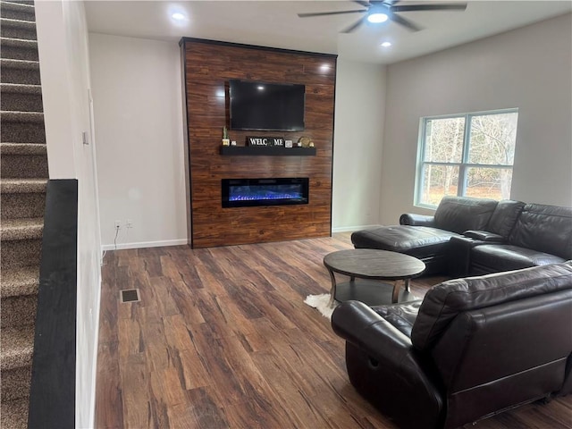 living room featuring wood finished floors, visible vents, baseboards, stairs, and a glass covered fireplace