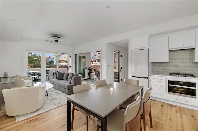 kitchen with white cabinetry, french doors, stainless steel appliances, decorative backsplash, and light wood-type flooring