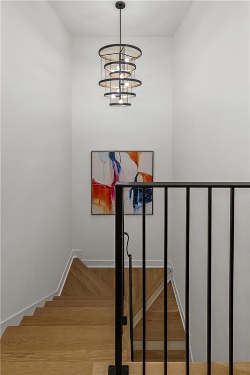 stairway with hardwood / wood-style flooring and an inviting chandelier