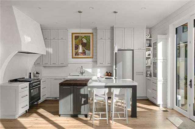 kitchen with a kitchen breakfast bar, gas stove, sink, a kitchen island, and hanging light fixtures