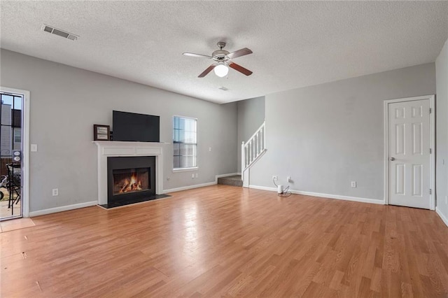 unfurnished living room featuring a textured ceiling, ceiling fan, and light hardwood / wood-style flooring