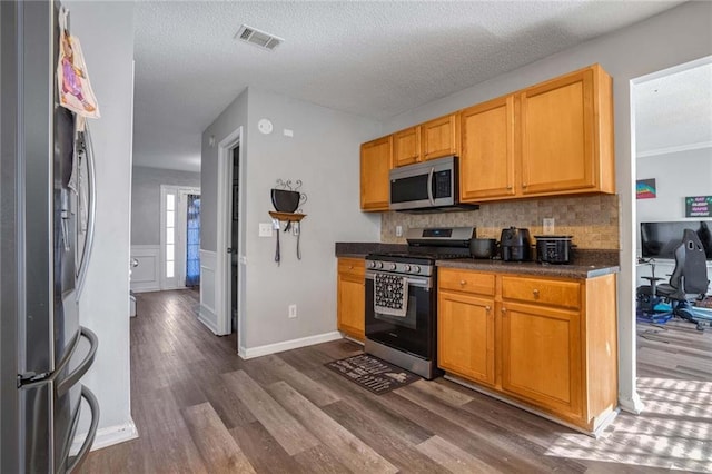 kitchen featuring decorative backsplash, dark wood-type flooring, stainless steel appliances, and a textured ceiling