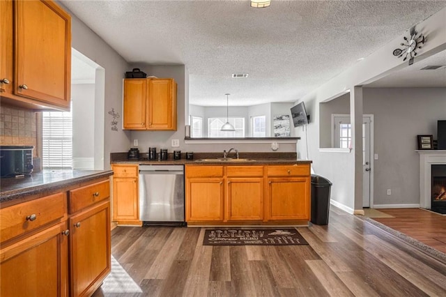 kitchen with sink, stainless steel dishwasher, light hardwood / wood-style floors, and decorative backsplash