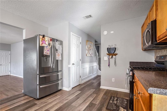 kitchen featuring dark hardwood / wood-style floors, a textured ceiling, and appliances with stainless steel finishes