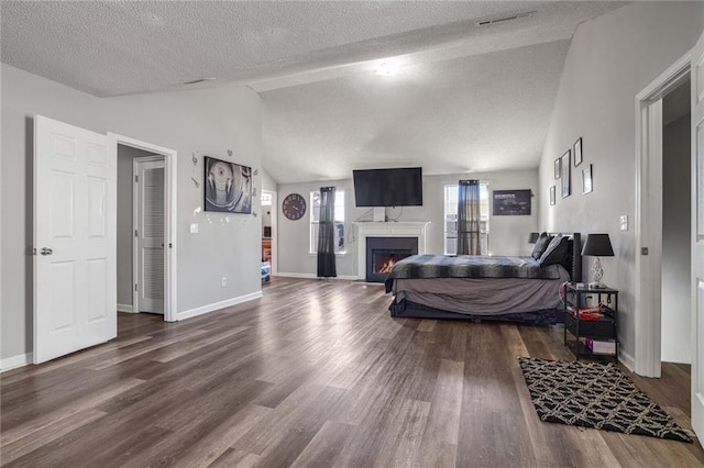 bedroom featuring wood-type flooring, vaulted ceiling, and a textured ceiling