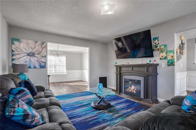 living room featuring wood-type flooring, a textured ceiling, and a notable chandelier