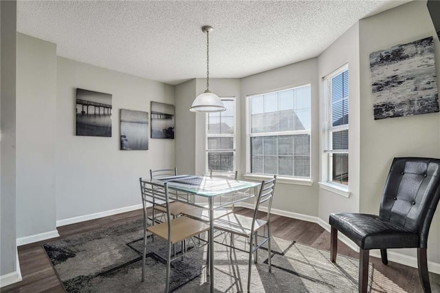 dining area featuring dark wood-type flooring and a textured ceiling