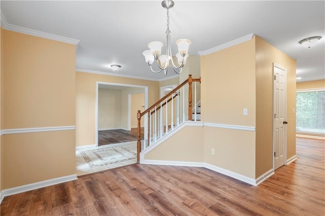 interior space featuring crown molding, baseboards, an inviting chandelier, and wood finished floors