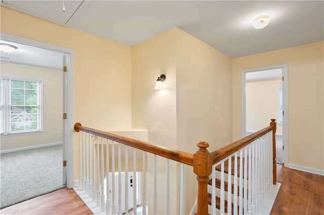 hall with baseboards, an upstairs landing, wood finished floors, and attic access
