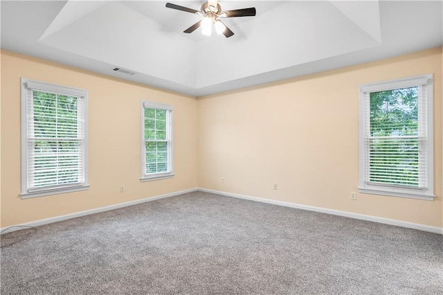 unfurnished room featuring ceiling fan, visible vents, a raised ceiling, baseboards, and carpet flooring