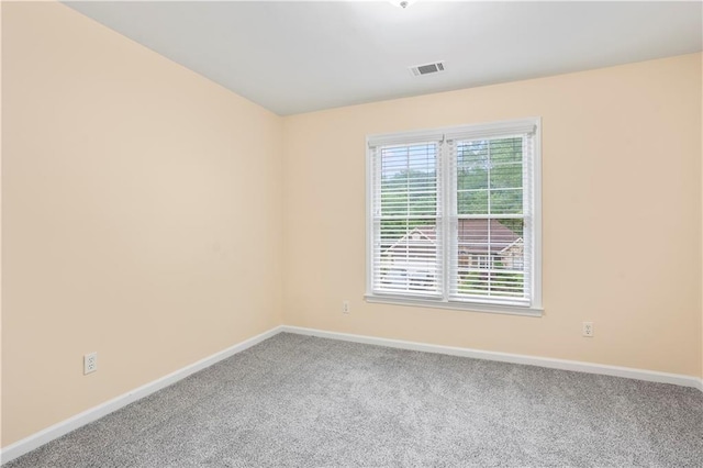 empty room with carpet floors, baseboards, and visible vents