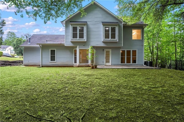back of property with a lawn, central AC, and roof with shingles