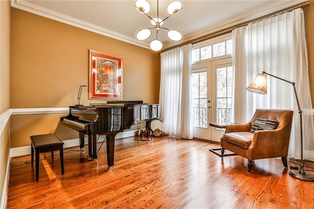 living area featuring an inviting chandelier, ornamental molding, and hardwood / wood-style flooring