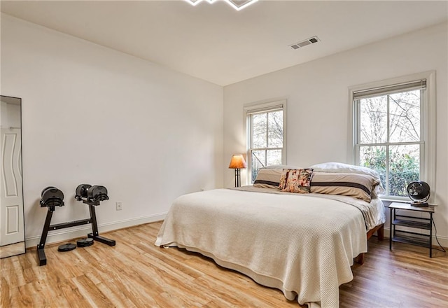 bedroom with multiple windows and hardwood / wood-style flooring