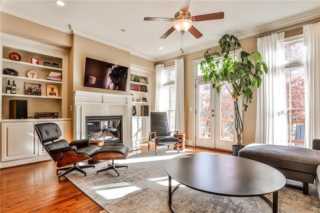 sitting room with ceiling fan, hardwood / wood-style flooring, a wealth of natural light, and built in shelves