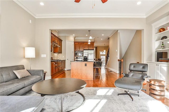 living room featuring ceiling fan, ornamental molding, and hardwood / wood-style floors