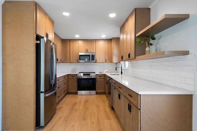 kitchen with open shelves, tasteful backsplash, appliances with stainless steel finishes, a sink, and light wood-type flooring