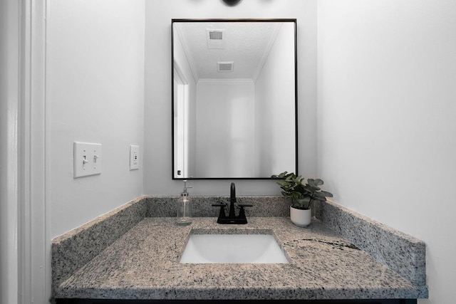 bathroom with visible vents, crown molding, a textured ceiling, and vanity