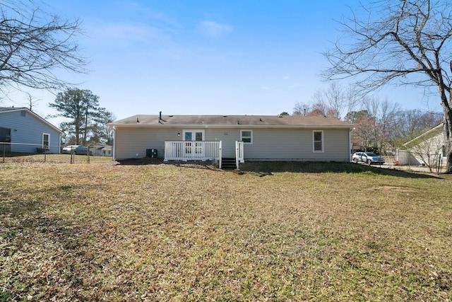 rear view of house featuring a lawn, fence, and a wooden deck