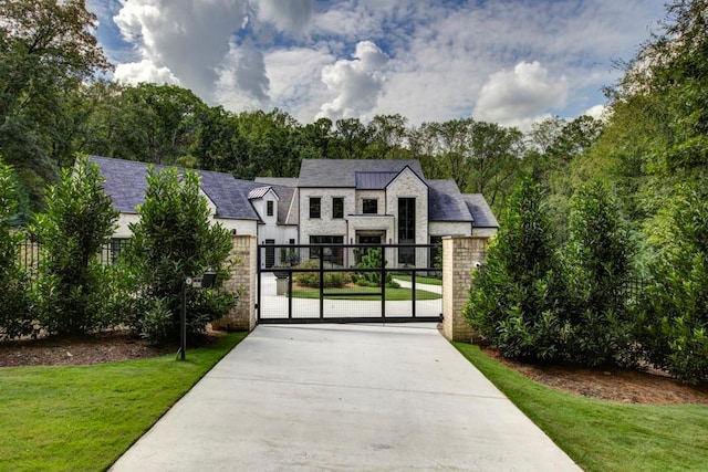 view of front facade with a front yard, stone siding, fence, and a gate