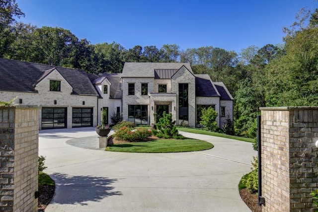 french country home featuring concrete driveway, a garage, and board and batten siding