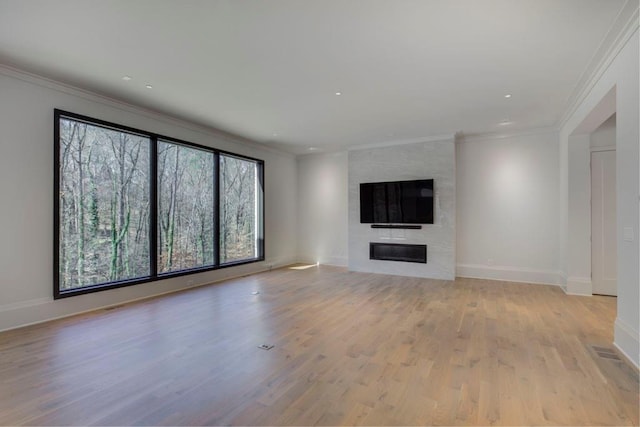 unfurnished living room with crown molding, a fireplace, light wood-style flooring, and baseboards