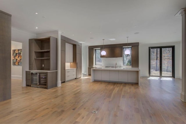 kitchen with light wood finished floors, light countertops, backsplash, ornamental molding, and modern cabinets