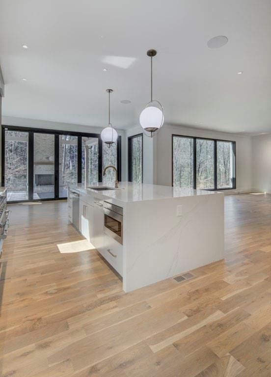 kitchen featuring open floor plan, light countertops, light wood-style flooring, and white cabinets