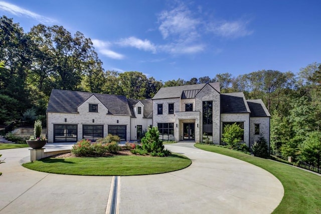 view of front of property with stone siding, driveway, a front lawn, and an attached garage