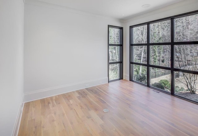 spare room with ornamental molding, visible vents, baseboards, and wood finished floors