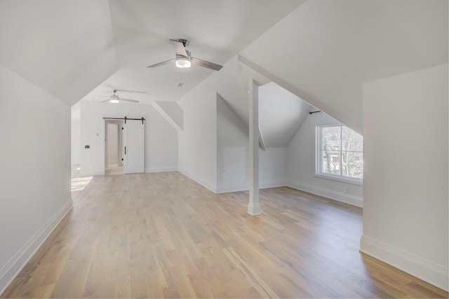 additional living space with ceiling fan, baseboards, vaulted ceiling, and light wood-type flooring