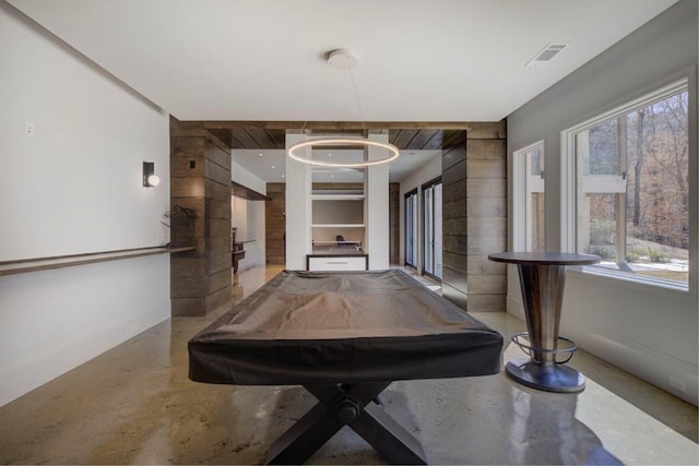 hallway with finished concrete floors, visible vents, baseboards, and a healthy amount of sunlight