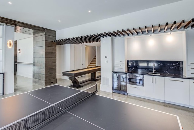 game room with finished concrete floors, recessed lighting, wet bar, and a sink